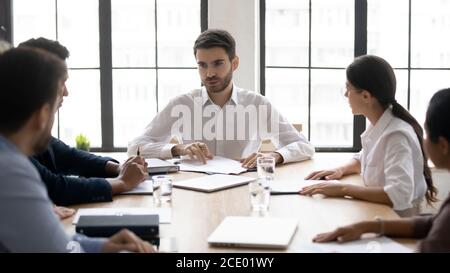 Millennial male mentor instructing mixed race teammates at workplace. Stock Photo