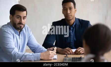 Focused young mixed race teammates listening to colleague in office. Stock Photo