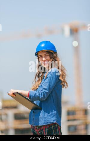 young woman working in construction site and holding clipboard with documents Stock Photo