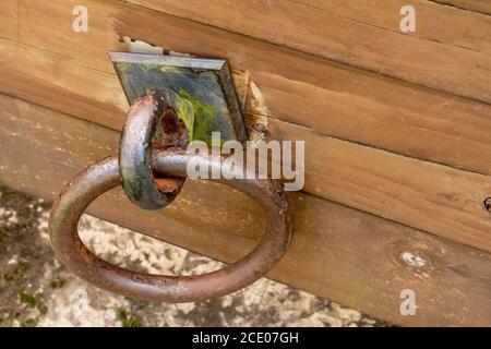 Rusty door ring on a wooden old cracked board close-up. Broken mount. View from above. Antique historical concept Stock Photo