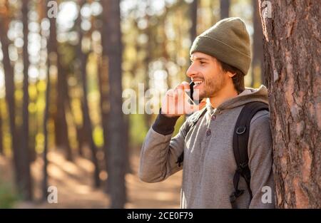 Happy young man backpacker talking on phone while hiking Stock Photo