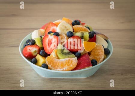 Decorative deep plate full of pieces of different types of fruit. Healthy and refreshing salad Stock Photo