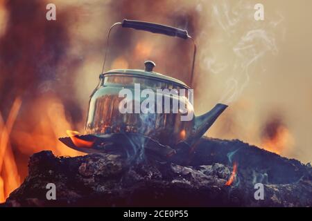 boiling kettle with steam on firewood and ash in winter forest Stock Photo  - Alamy