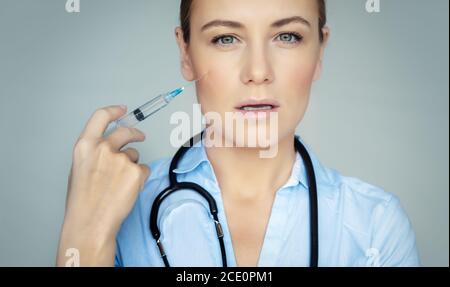 Portrait of a Beautiful Woman Doctor with a Beauty Shot Isolated on Gray Background. Anti-aging or Anti-wrinkle Injection. Cosmetology Clinic. Stock Photo