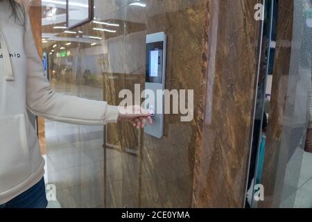 The girl calls the Elevator, ride the Elevator in the office, shopping center or business center to the second floor. The hand presses a button on the Stock Photo