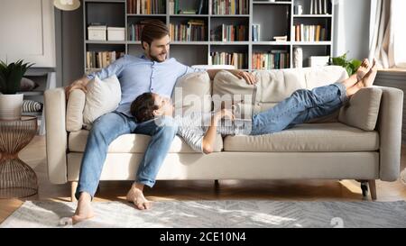Pleasant young woman using computer applications, lying on man laps. Stock Photo