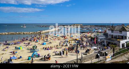 Lyme Regis, Dorset, UK. 30th Aug, 2020. UK Weather: Beachgoers and families flock to the packed beach at the seaside resort of Lyme Regis on Bank Holiday Sunday to soak up the last of the hot sunshine. Credit: Celia McMahon/Alamy Live News
