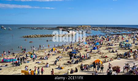 Lyme Regis, Dorset, UK. 30th Aug, 2020. UK Weather: Beachgoers and families flock to the packed beach at the seaside resort of Lyme Regis on Bank Holiday Sunday to soak up the last of the hot sunshine. Credit: Celia McMahon/Alamy Live News