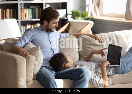 Relaxed woman lying on man laps, involved in online shopping. Stock Photo