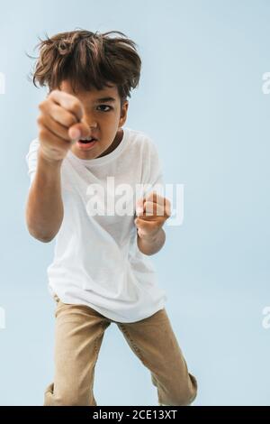 Aggressive asian kid poking camera with poorly closed fists, pretending to punch Stock Photo