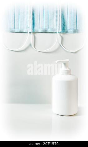 Coronavirus prevention concept. Blue medical mask and white plastic pump bottle hand sanitizer gel or soap dispenser. Stock Photo