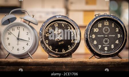 Three Vintage alarm clocks on  a wooden shelf close up front image,   Two black without hands and one white Stock Photo
