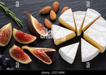 Camembert cheese with figs and almonds on black slate. Cheese appetizer plate Stock Photo