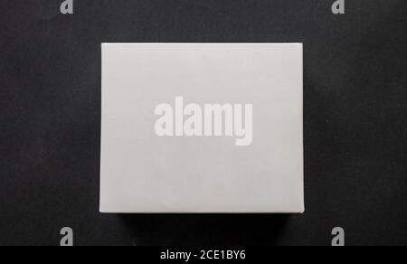 Package box rectangle, blank advertise template for products packaging. White color empty closed cardboard container against black background, top vie Stock Photo