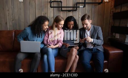 Happy diverse friends having fun together, looking at tablet screen Stock Photo