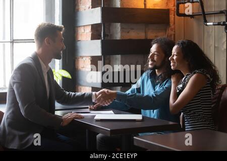 Smiling young African American couple making deal with realtor Stock Photo