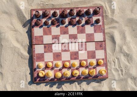 Chess play on the board at the beach. Chessboard on the sand on a sunny day. Stock Photo
