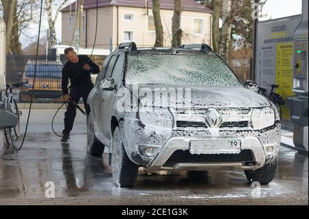 a man washes his car, a man at a car wash, a Renault in foam at a car wash, Russia, Kaliningrad region, March 1, 2020 Stock Photo