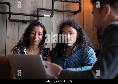 Happy young African American couple listening to realtor at meeting Stock Photo