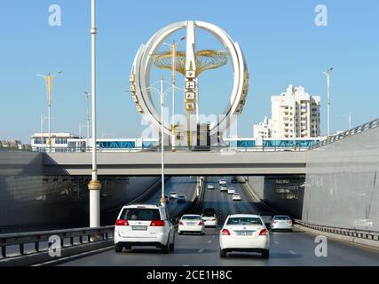 Highway in Ashgabat showing only white cars vehicle allowed. Avenue with white car traffic in Turkmenistan. Monument with gold details. Stock Photo