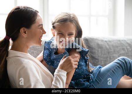 Overjoyed young woman having fun with laughing little daughter. Stock Photo