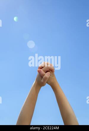 Closeup two young hands holding each other on the blue background  Stock Photo