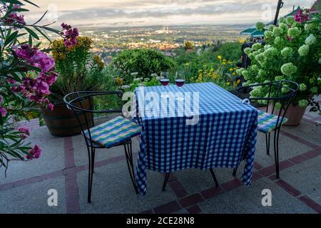 classic terrace furniture with beautiful view of city Pecs in Hungay with two wine glasses on the table romantic outdoor setting Stock Photo