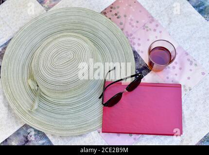 Outdoor garden setting for relaxing summer season afternoon reading with cool beverage and wide brimmed hat on at home vacation Stock Photo