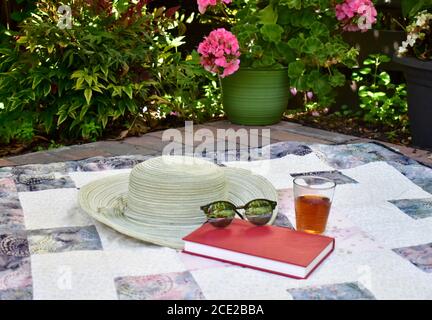Outdoor garden setting for relaxing summer season afternoon reading with cool beverage and wide brimmed hat on at home vacation Stock Photo