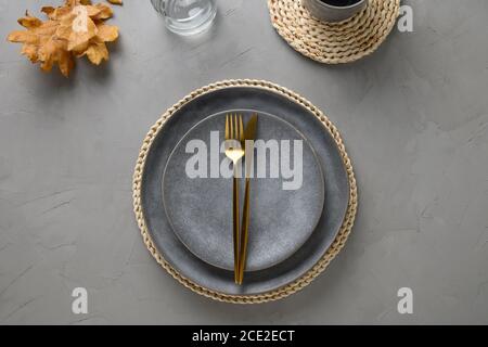 Elegant table setting with autumn oak leaves and golden cutlery on grey background. Flat lay, top view Stock Photo