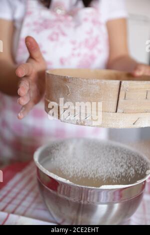 Woman using sieve with flour in order to bake homemade bread Stock Photo