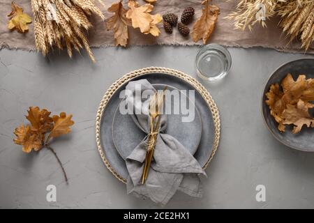 Autumn table setting with seasonal harvest and gold decor on grey. Stock Photo