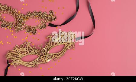 Golden carnival masks and confetti on pastel pink background. Flat lay, top view. Christmas, Masquerade concept Stock Photo