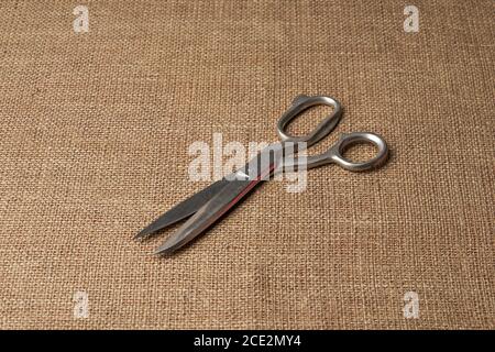 Old steel tailor scissors on brown burlap Stock Photo