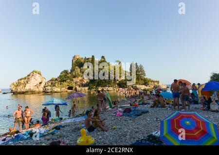 Taormina, Sicily, south Italy - August 27 2020 -  Crowded beach in taormina next to the famus Isola Bella in the background. Stock Photo