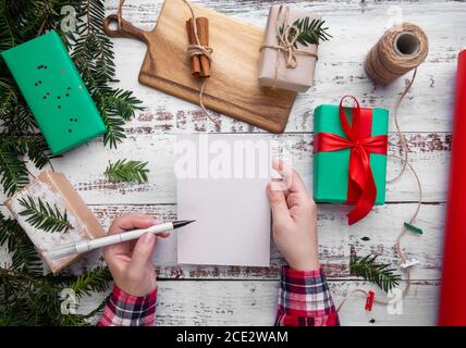 hands hold a pen and a postcard on the table next to gifts Stock Photo