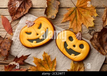 Halloween gingerbread pumpkins on wooden table with autumn leaves Stock Photo