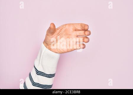 Hand of caucasian young man showing fingers over isolated pink background holding invisible object, empty hand doing clipping and grabbing gesture Stock Photo