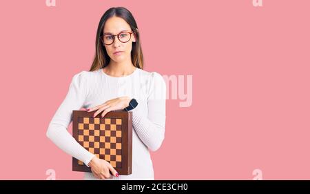 Pensive woman sitting at table in living room while thinking about next  chess move. Stock Photo by DC_Studio