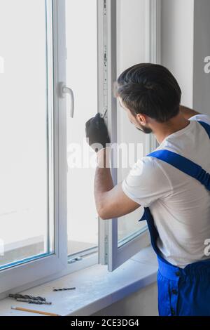 Worker in overalls preparing to install a window Stock Photo