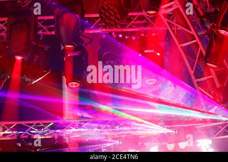 Modern stage lighting equipment at a concert. LED moving heads, lasers, and other lighting fixtures hanging on truss. Selective focus. Stock Photo