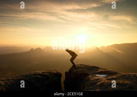 Man in black jumping between peaks. Dreamy daybreak Stock Photo