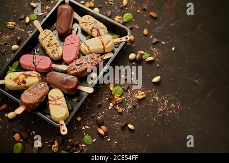 Set of delicious white and milk chocolate and strawberry ice cream on a stick served in metal tray Stock Photo
