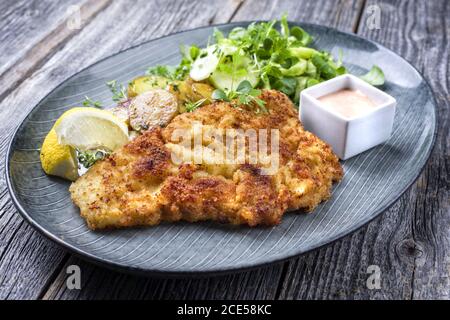 Fried Wiener schnitzel from veal topside with fried potatoes and lettuce as closeup modern design plate Stock Photo