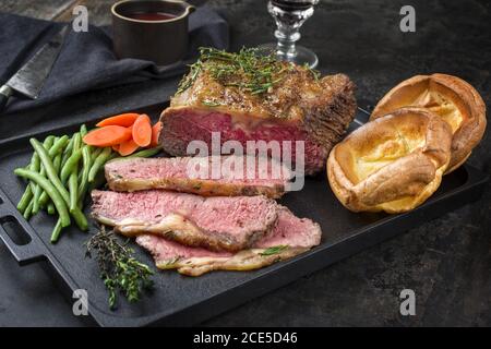 Traditional Commonwealth Sunday roast with sliced cold cuts roast beef with vegetable and Yorkshire pudding as closeup on a mode Stock Photo