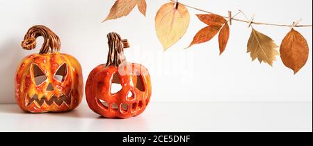 Banner with Ceramic Jack Lanterns and autumn leaves garland on table wall background Stock Photo