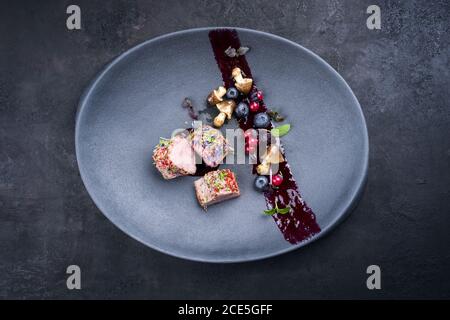 Fried dry aged venison tenderloin fillet medallion steak natural with mushrooms and forest berries as top view on a modern desig Stock Photo