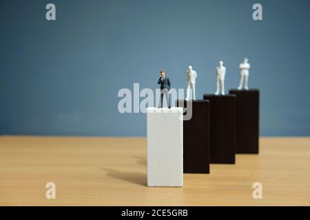 Business strategy conceptual photo – miniature of businessman stands on wooden wall Stock Photo