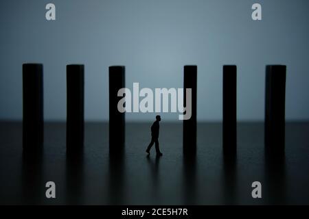 Business strategy conceptual photo – silhouette miniature of businessman walking in the middle of barrier wall Stock Photo