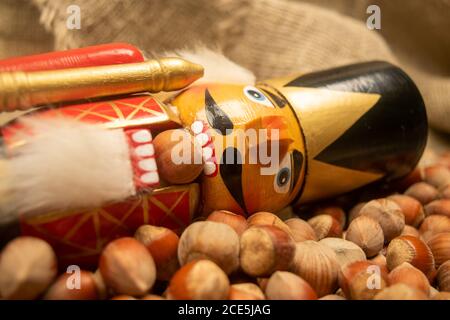 Nutcracker wooden figure of a soldier for cracking nuts on the background of scattered nuts. Traditional symbol of Christmas and New Year. Close up Stock Photo